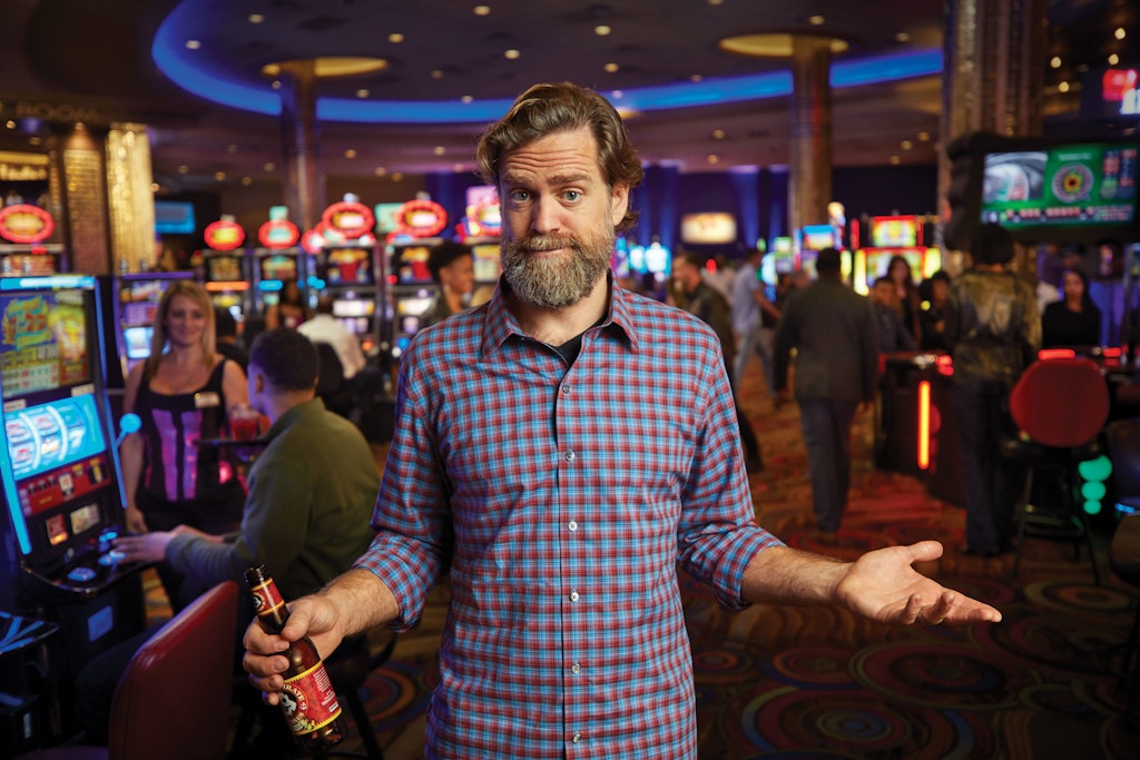Man standing at a casino in front of slot machines and table games